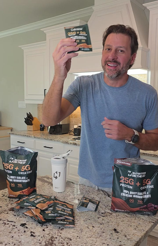 Dallas C. holding a Nutrition On The Go Cinnamon Roll packet in his kitchen